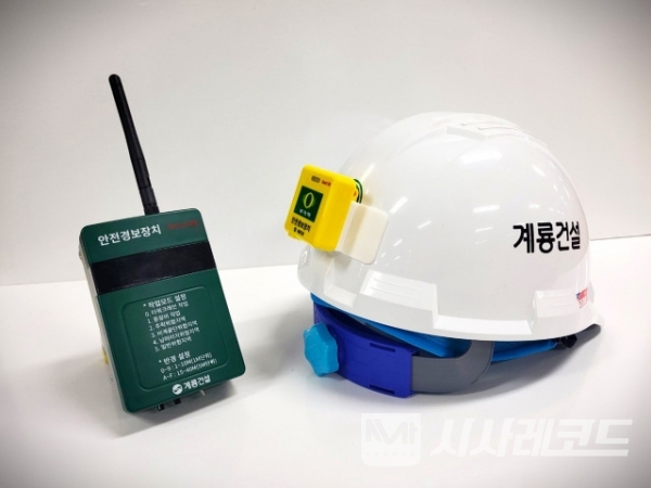 안전경보장치 송신기(왼쪽 초록색 기기)와 수신기(오른쪽 안전모에 부착된 노란색 기기)/자료=계룡건설